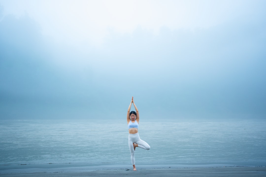 A woman standing on one leg on a beach