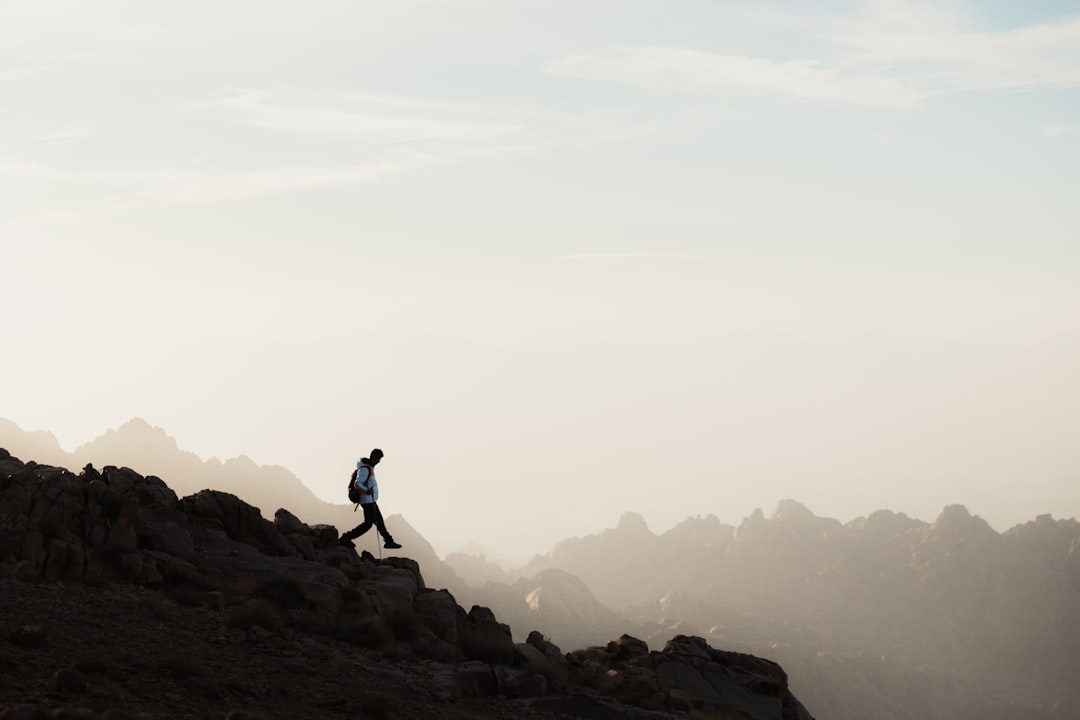 a man running up a mountain with a sky background